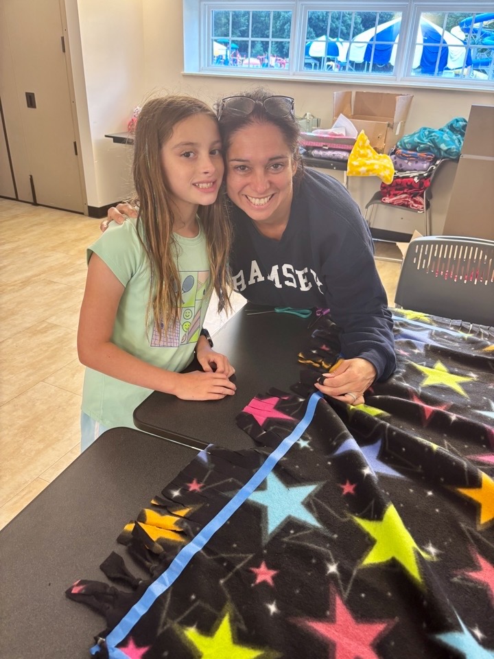 Young volunteers working together on a colorful fleece blanket