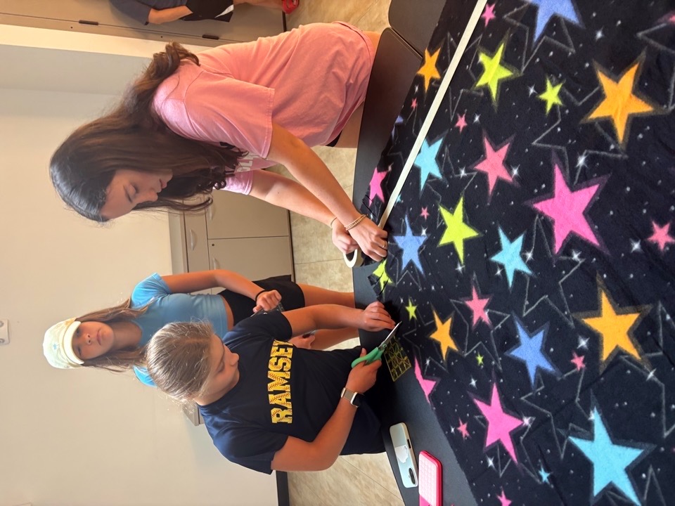 Volunteers gathering around a blanket-making table