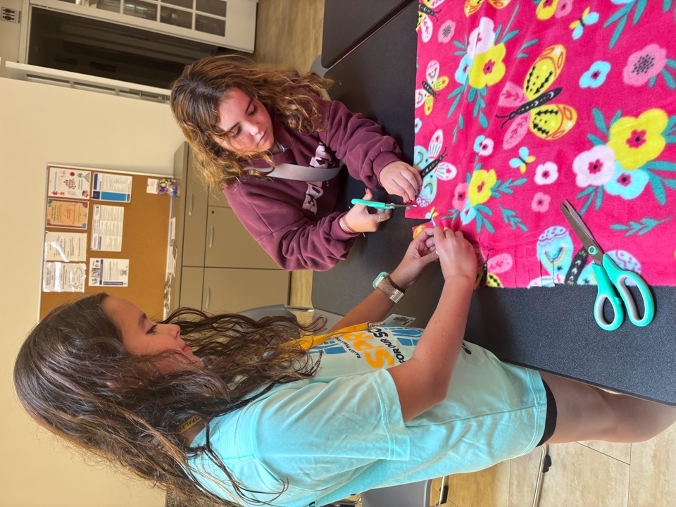 Community members making fleece tie blankets together