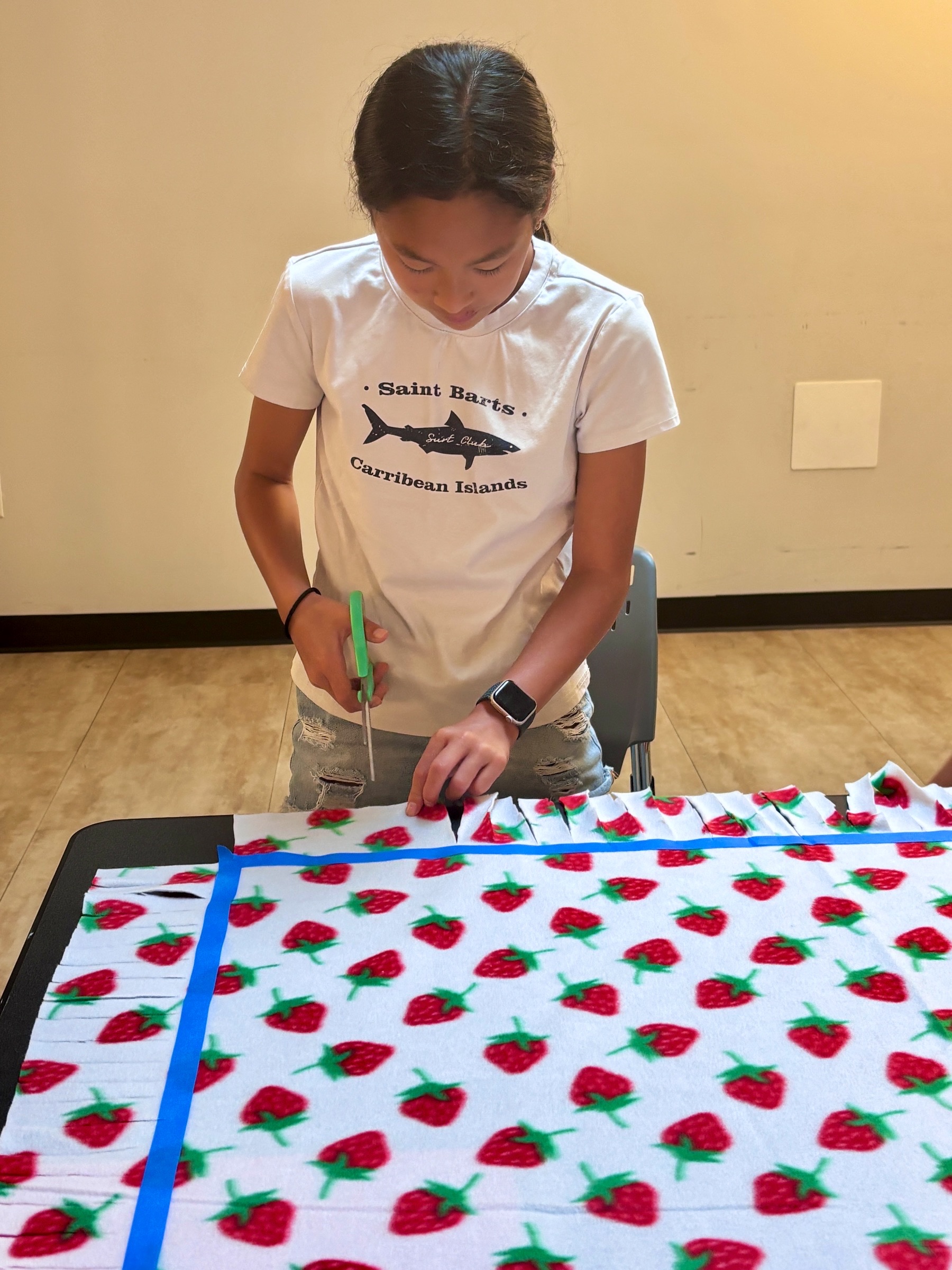 Young volunteer making a fleece tie blanket at the community event