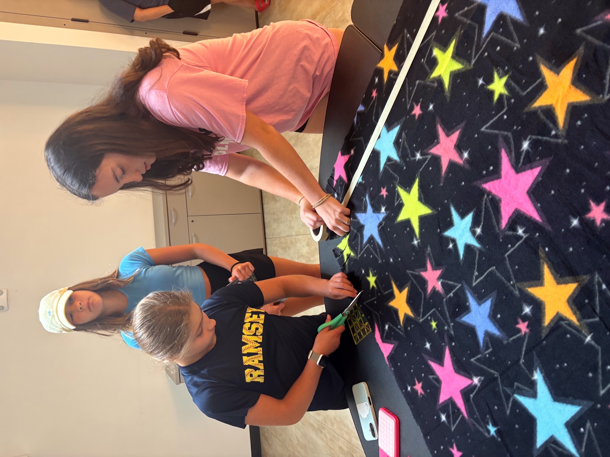Volunteers gathering around a blanket-making table